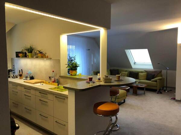 Moderne offene Küche mit Bartresen und gemütlichem Wohnzimmer mit Dachschräge.